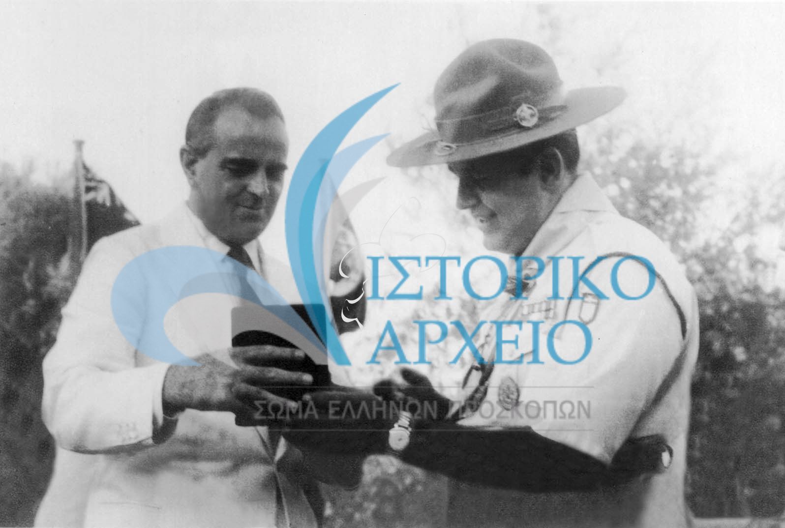 Ο Πρωθυπουργός Κωνσταντίνος Καραμανλής παραλαμβάνει από τον ΓΕ Δ. Αλεξάτο Αναμνηστικό του Τζάμπορη Αποδήμων του 1956 στον Άγιο Ανδρέα.