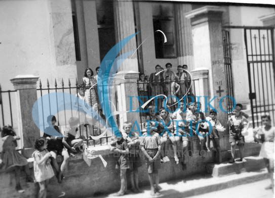 Πρόσκοποι με πολιτική περιβολή βοηθούν στα συσσίτια που οργάνωνε η Εθνική Οργάνωση Χριστιανικής Αλληλεγγύης - ΕΟΧΑ. Εδώ στο Δημοτικό Σχολείο Πλάκας το 1943.  