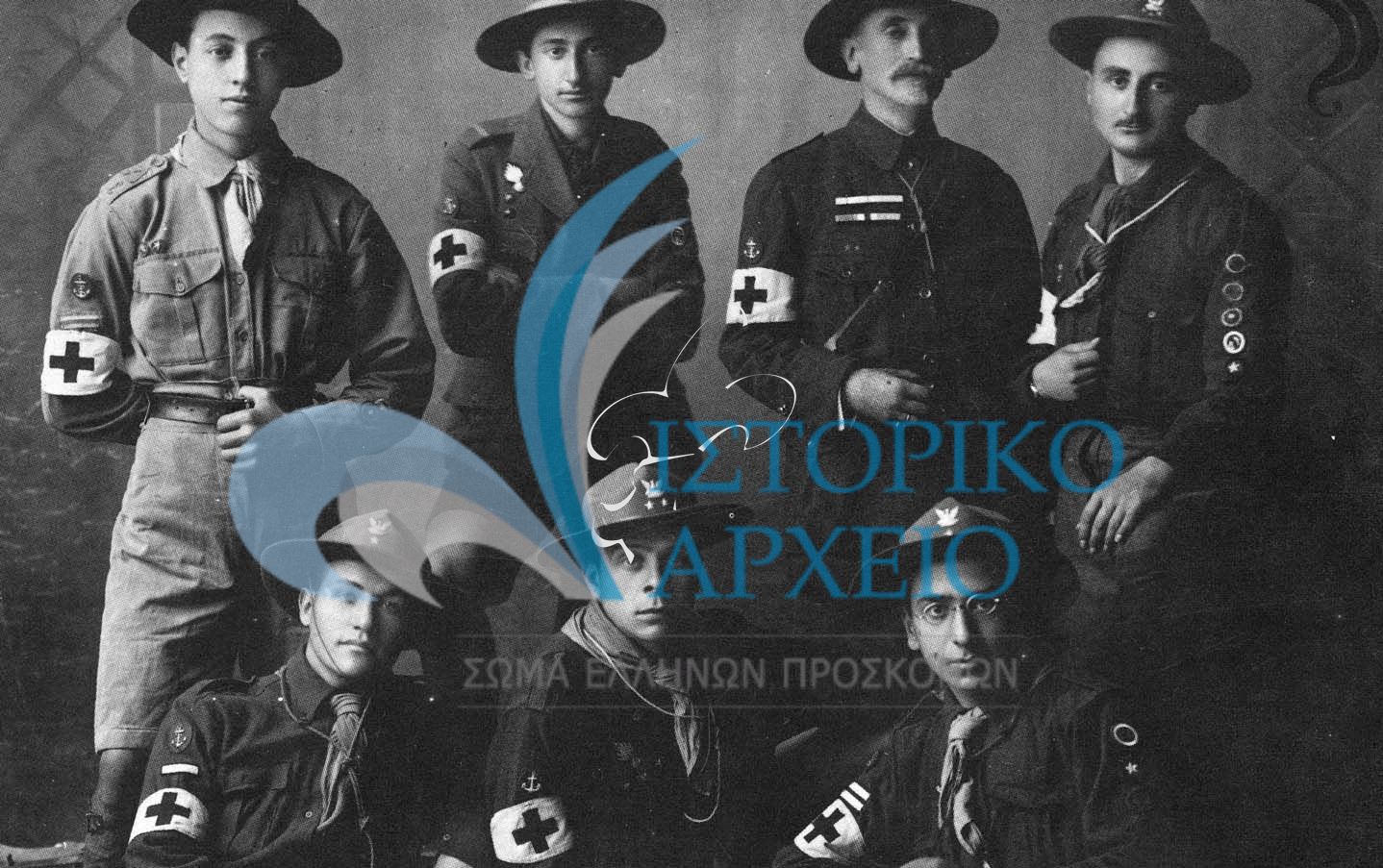Η πρώτη ομάδα τραυματιοφορέων προσκόπων που κατείχαν δίπλωμα από τον Ελληνικό Ερυθρό Σταυρό. Η ομάδα πρόσφερε πολύτιμες υπηρεσίες στους τραυματίες κατά τα γεγονότα του "εθνικού διχασμού" τον Νοέμβριο του 1916. Από δεξιά: Η. Ησαϊας, Μ. Μίνδλερ, Γ. Μίνδλερ, Στ. Νίκογλου, Αντ. Σαρηγιάννης, Λ. Γορτσίδης, Λ. Μαλακατές.