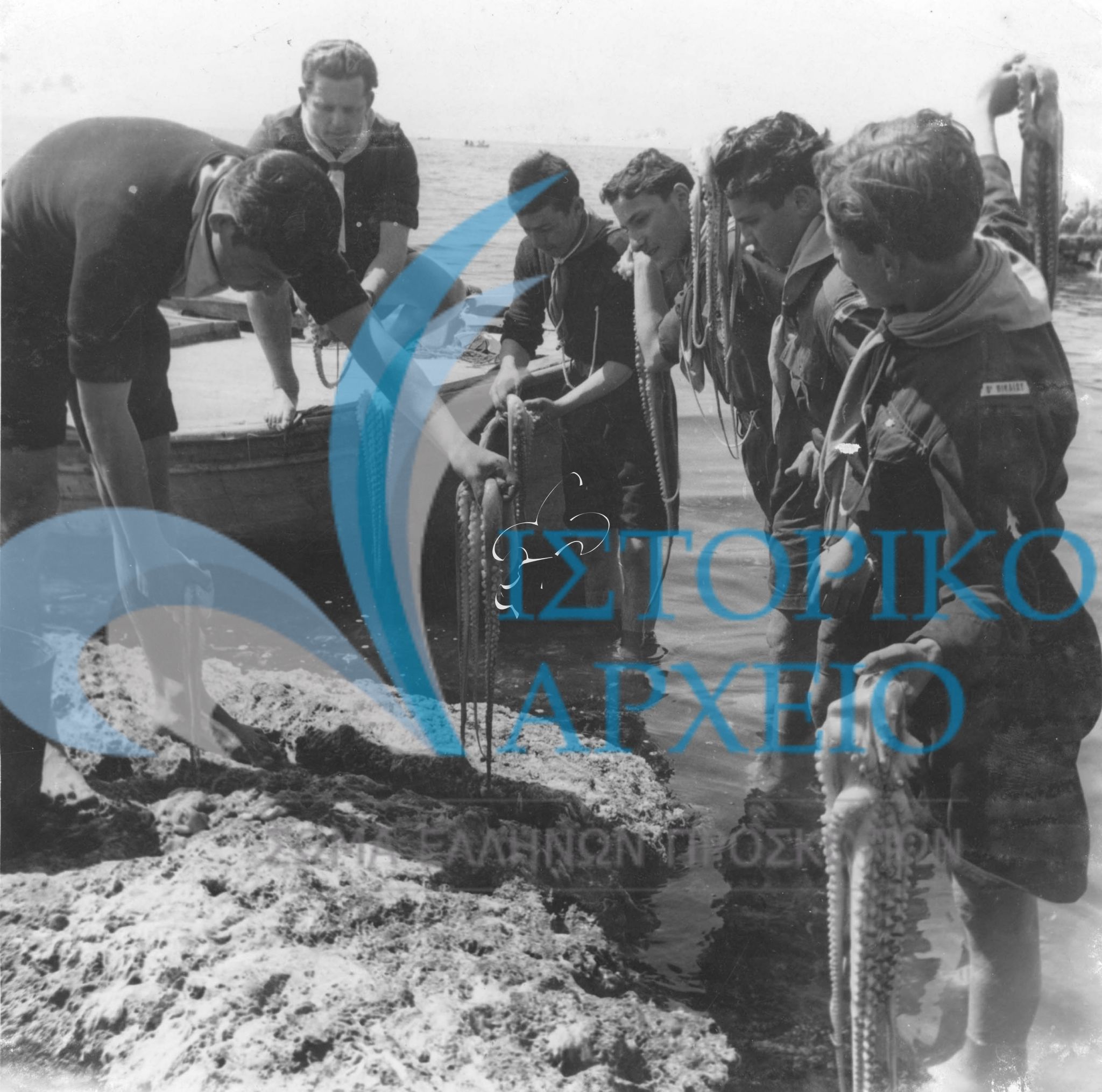 Πρόσκοποι της 3ης Ομάδας Νίκαιας μετρούν τα χταπόδια που ψάρεψαν στην εκδρομή τους στην Γλυφάδα τον Απρίλιο του 1948. Η φωτογραφία είχε δημοσιευθεί στο περιοδικό "Ναυτική Ελλάς" τον ίδιο χρόνο.
