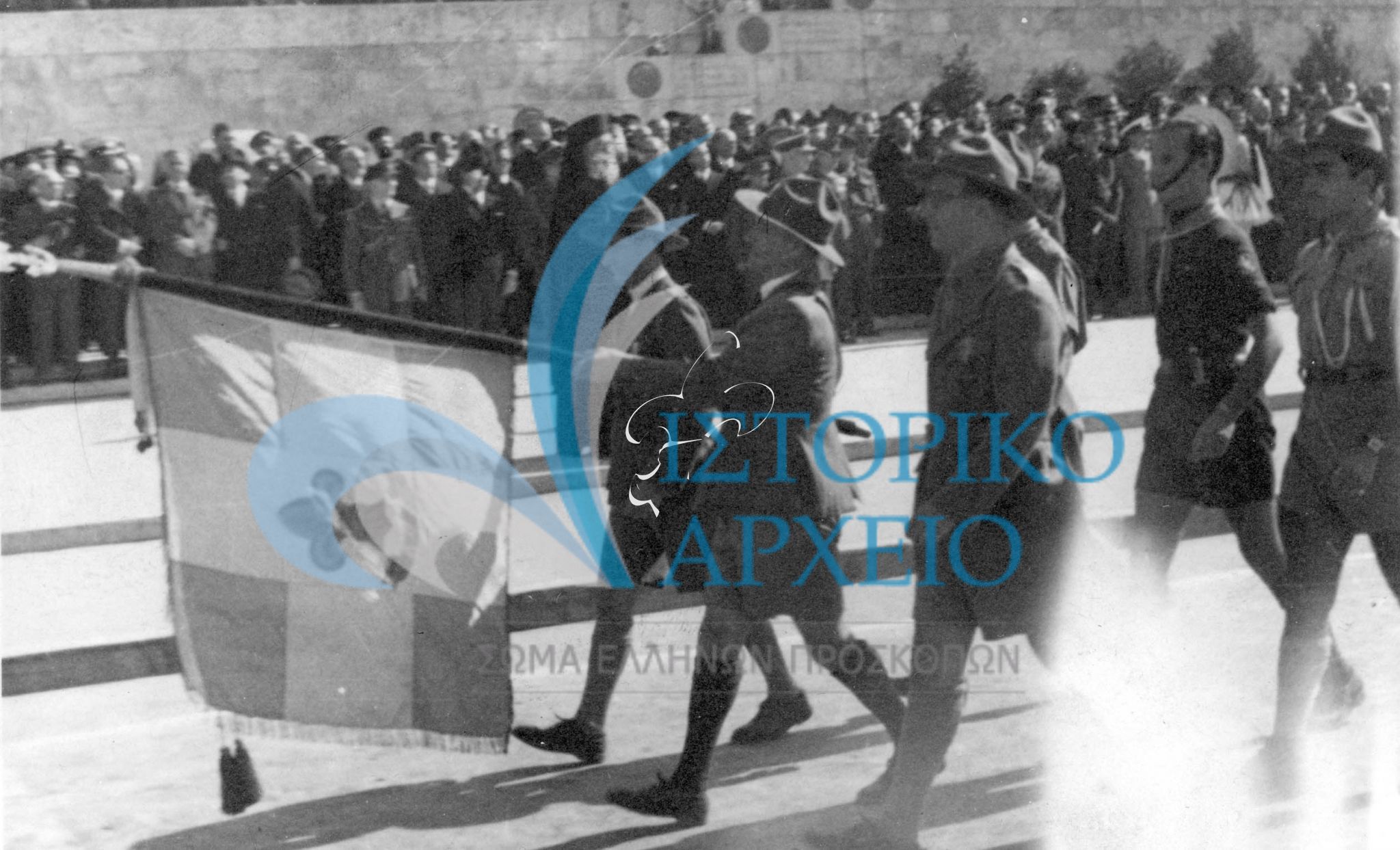 Πρόσκοποι χαιρετούν με την Σημαία του ΣΕΠ τον Αντιβασιλέα Αρχιεπίσκοπο Αθηνών & Πάσης Ελλάδος Δαμασκηνό κατά την παρέλαση της 25ης Μαρτίου 1946 στην Αθήνα.