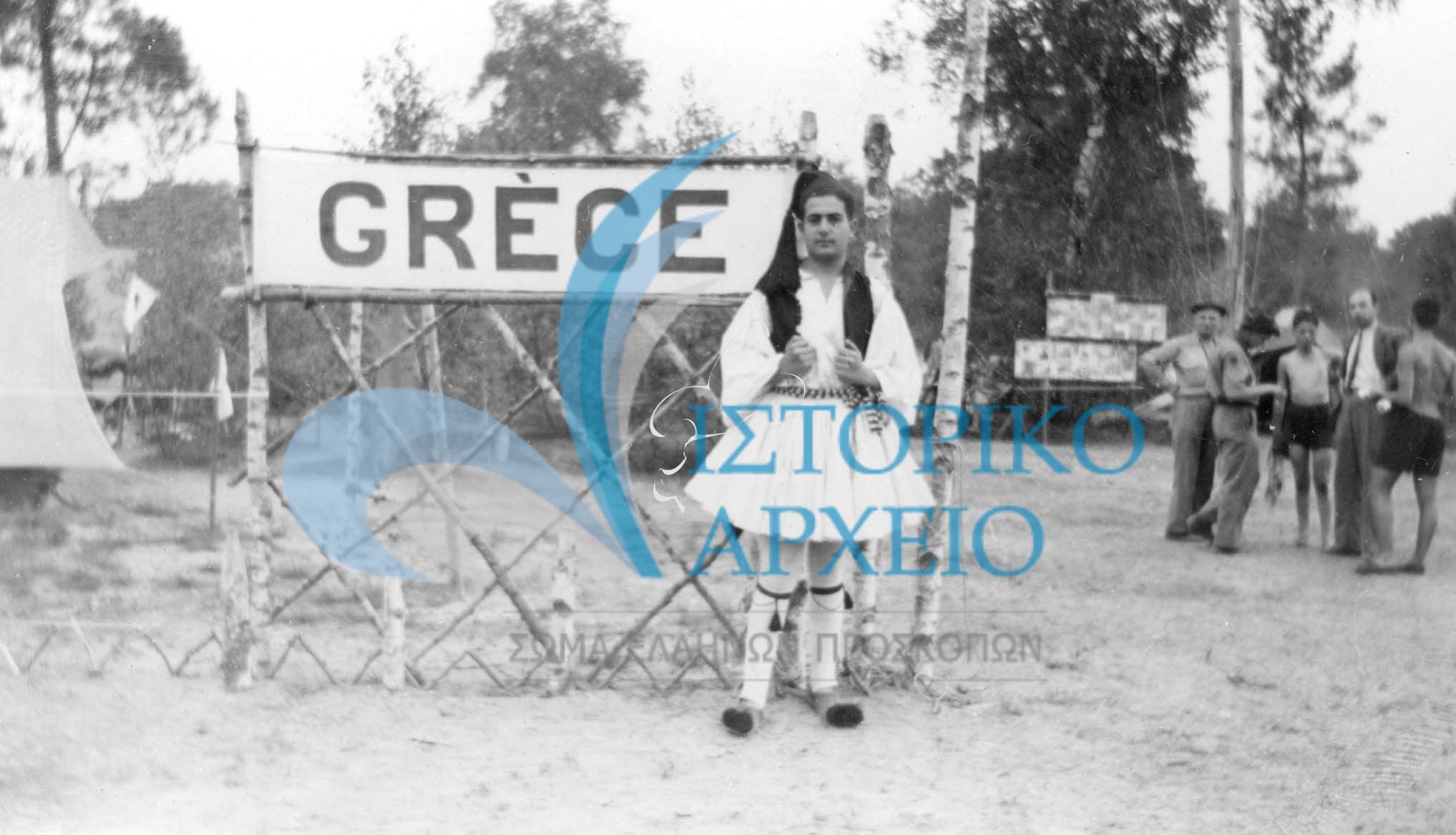 Έλληνας πρόσκοπος με εθνική ενδυμασία στη πύλη της ελληνικής κατασκήνωσης του Τζάμπορη Γαλλίας το 1947.