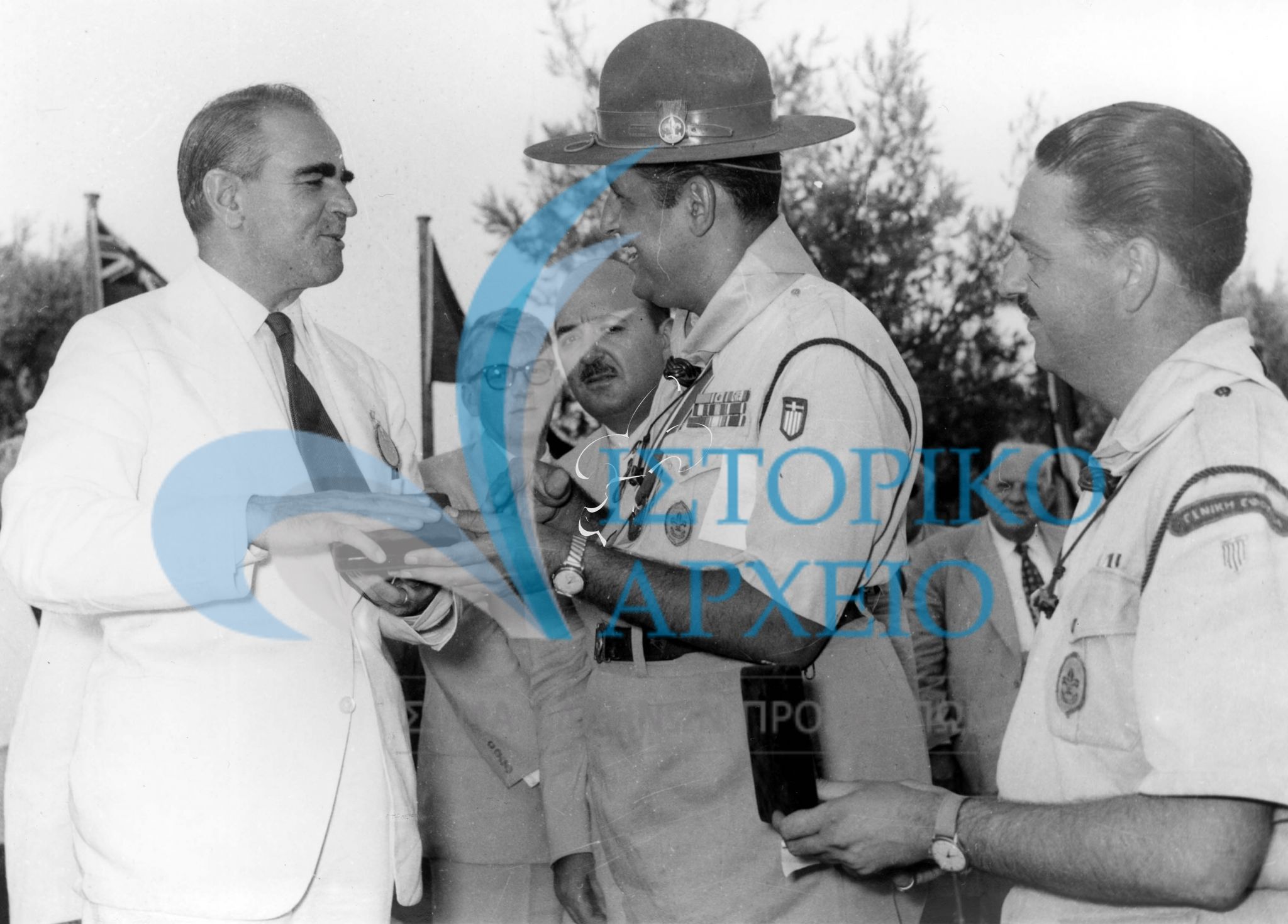 Ο Πρωθυπουργός Κωνσταντίνος Καραμανλής λαμβάνει αναμνηστικό σήμα του Πανελληνίου Τζάμπορη Αποδήμων από τον Γενικό Έφορο Δ. Αλεξάτο τον Αύγουστο του 1956.