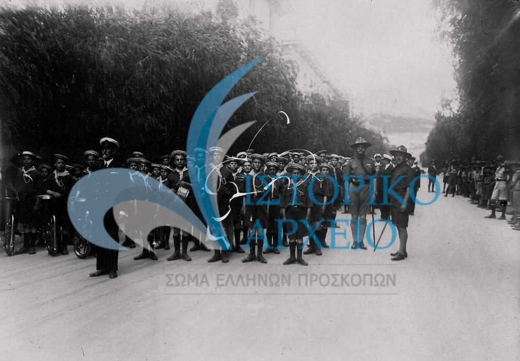 Ναυτοπρόσκοποι της Αθήνας μαζί με προσκοπική μπάντα σε παράταξη σε δρόμο του Κολωνακίου το 1926 κατά τη διάρκεια της Α' Πανελλήνια Συνάντηση. Δίπλα τους στέκει ο Αντώνης Μπενάκης.