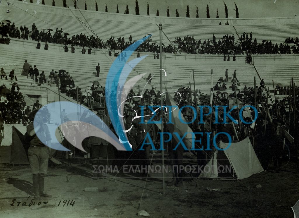 Ο Α. Φέτσης με προσκόπους του Β` Συστήματος ομάδων Αθηνών σε έπαρση Σημαίας στην προσκοπική επίδειξη στο Παναθηναϊκό Στάδιο το 1914.