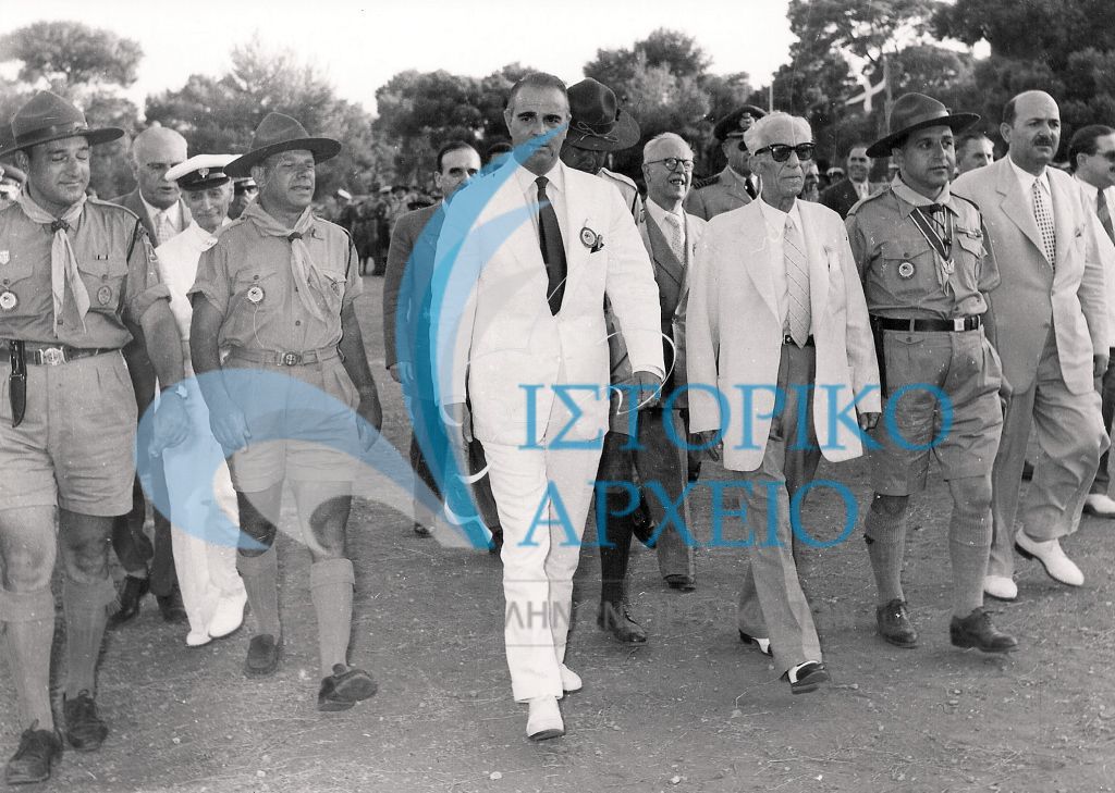 Ο Πρωθυπουργός Κωνσταντίνος Καραμανλής με τον Υπουργό Εθνικής Παιδείας & Θρησκευμάτων Πέτρο Λεβάντη  προσέρχονται στην Πυρά Έναρξης του Τζάμπορη Αποδήμων το 1956. Συνοδεύονται από τους: Δ. Αλεξάτο, Δ. Μακρίδη, Μ. Σοφιανό και Σκυριανίδη.