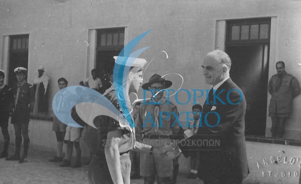 Ο Έλληνας Πρεσβευτής στην Αλεξάνδρεια Μιχ. Μελάς χαιρετά ενωμοτάρχη Ναυτοπροσκόπων κατά την εκδήλωση υποδοχής του το 1952. Διακρίνονται επίσης οι: Μαθάς και Βασιλείου.