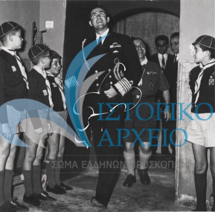 Ο Βασιλιάς Κωνσταντίνος χαιρετάει τα λυκόπουλα που τον υποδέχονται στην εστία του 7ου Αγ. Δημητρίου κατά την έναρξη της 1η Σχολής Εκπαίδευσης Διακριτικού Δάσους στην Θεσσαλονίκη.