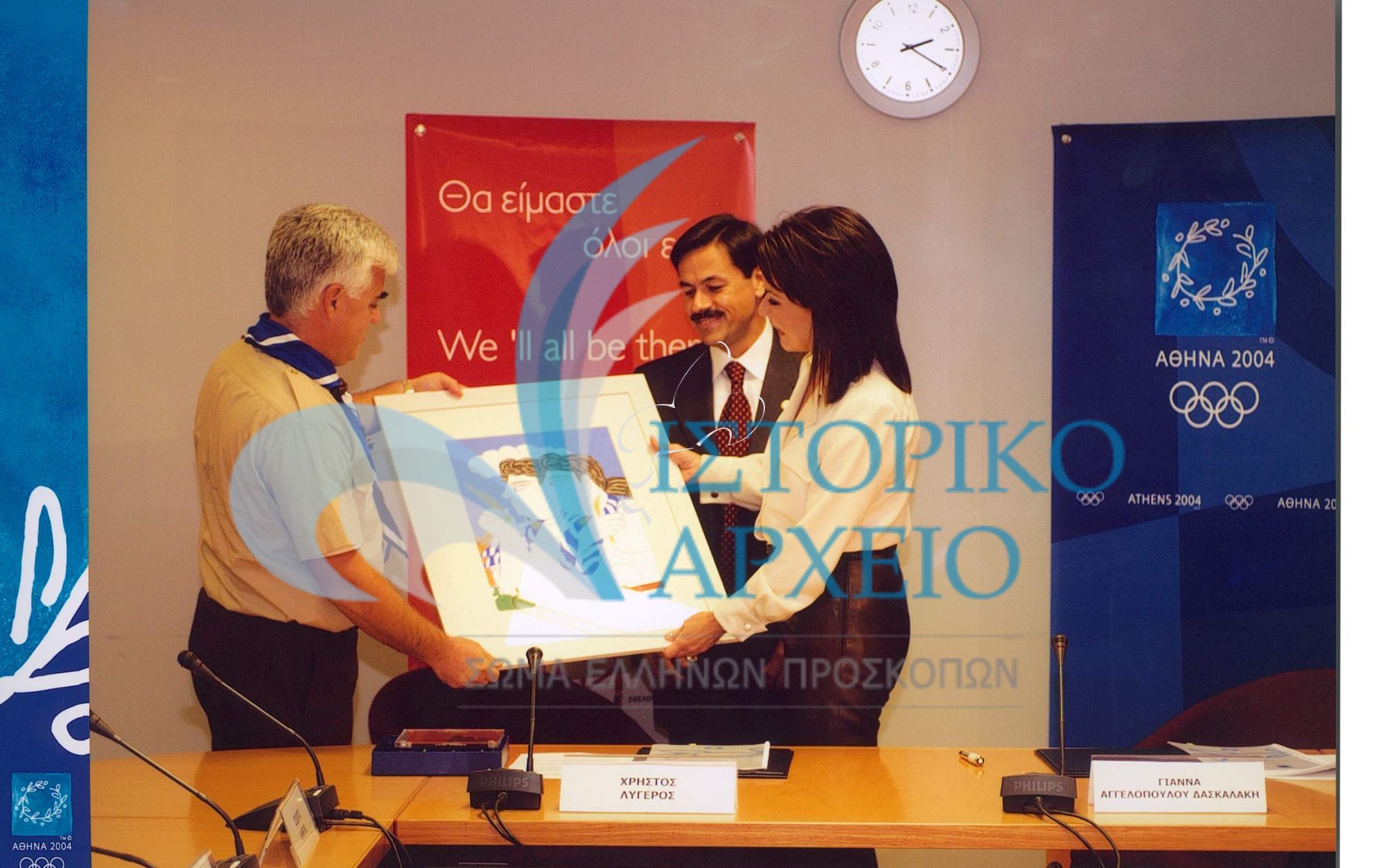 Ο Γεν. Έφορος Ισ. Κανέτης δίνει στην Πρόεδρο της Οργανωτικής Επιτροπής Ολυμπιακών Αγώνων "Αθήνα 2004" Γ. Αγγελοπούλου - Δασκαλάκη τον πίνακα του Αλ. Φασιανού "Πρόσκοποι", κατά την υπογραφή μνημονίου συναντίληψης και συνεργασίας, παρουσία του Προέδρου του ΔΣ ΣΕΠ Χ. Λυγερού. 