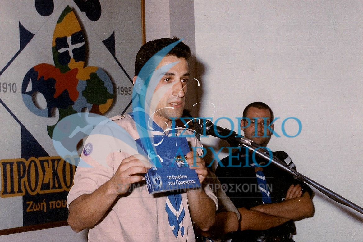Ο Γρηγόρης Μουρίκης ως σχεδιαστής του νέου Προσκοπικού Εγκολπίου το παρουσιάζει στην προσκοπική κίνηση το 1999.