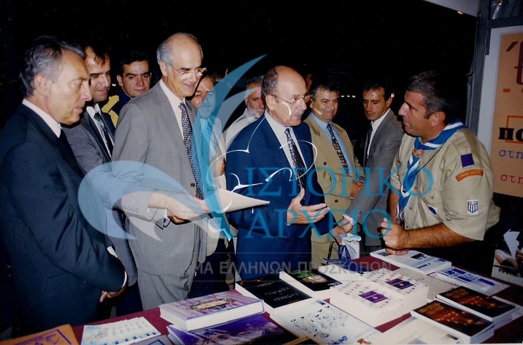Ο Πρόεδρος της Δημοκρατίας Κ. Στεφανόπουλος με τον Πρόεδρο της Βουλής των Ελλήνων Απ. Κακλαμάνη υποδεχόμενη από τον έφορος Δημ. Σχέσεων Μ. Καζάζη στο περίπτερο του ΣΕΠ κατά τα εγκαίνια Έκθεσης Βιβλίου το 2001.