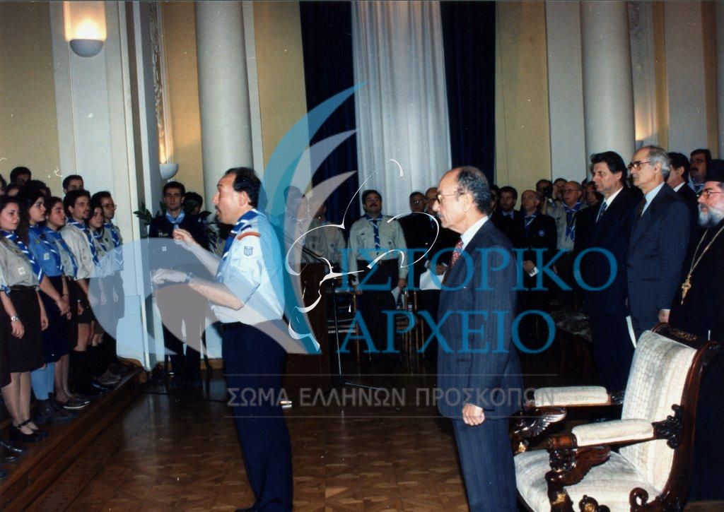 Ο Πρόεδρος της Δημοκρατίας Κωνσταντίνος Στεφανόπουλος στην εκδήλωση απονομής της διάκρισης "Πρόσκοπος Έθνους" το 1996. Την χωροδία προσκόπων διευθύνει ο έφορος Τ. Αρνιακός.