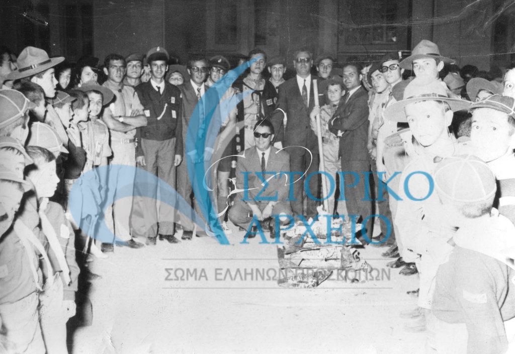 Πρόσκοποι και πλήθος κόσμου στην πυρά μετά την υπόσχεση νέων λυκοπούλων στην περιοχή Άγιος Κωνσταντίνος Αγρινίου το 1971. Διακρίνεται ο Νομάρης Αιτωλοακαρνανίας Ι. Καλογεράτος, ο ΤΕ ΑγρινίουΖόλδερ, ο ΑΣ Αντ. Μαστοράκης.