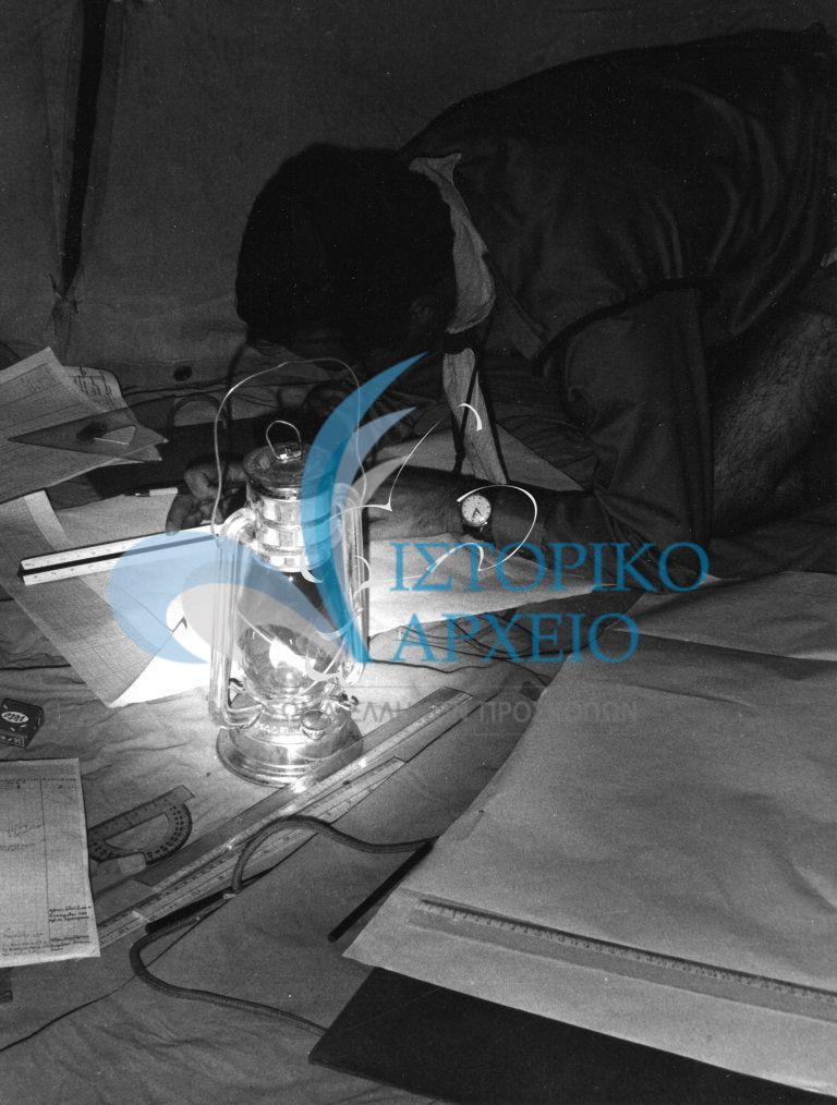 Πρόσκοπος σε εργασίες τοπογραφίας υπό το φως μιας λάμπας θυέλλης μέσα στην σκηνή του κατά τη διάρκεια εκπαίδευσης.