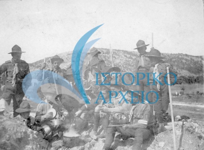 Πρόσκοποι της 7ης Ομάδας Αθηνών σε προετοιμασία μεσημεριανού φαγητού σε εκδρομή στο Δαφνί το 1913. Η φωτογραφία δόθηκε με αφιέρωση του αρχηγού Πεσματζόγλου στον Αθ. Λευκαδίτη.