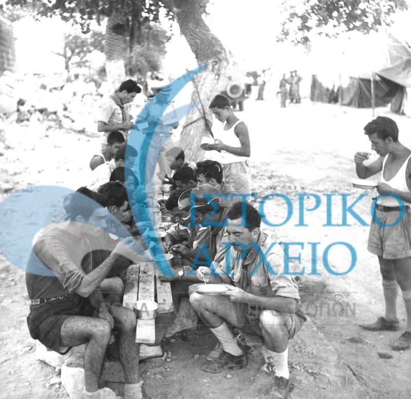 Πρόσκοποι που είχαν πρόσφεραν υπηρεσίες στην σεισμόπληκτη περιοχή της Ζακύνθου το 1953 σε ώρα πρωινού ροφήματος στην πρόχειρη κατασκήνωσή τους.