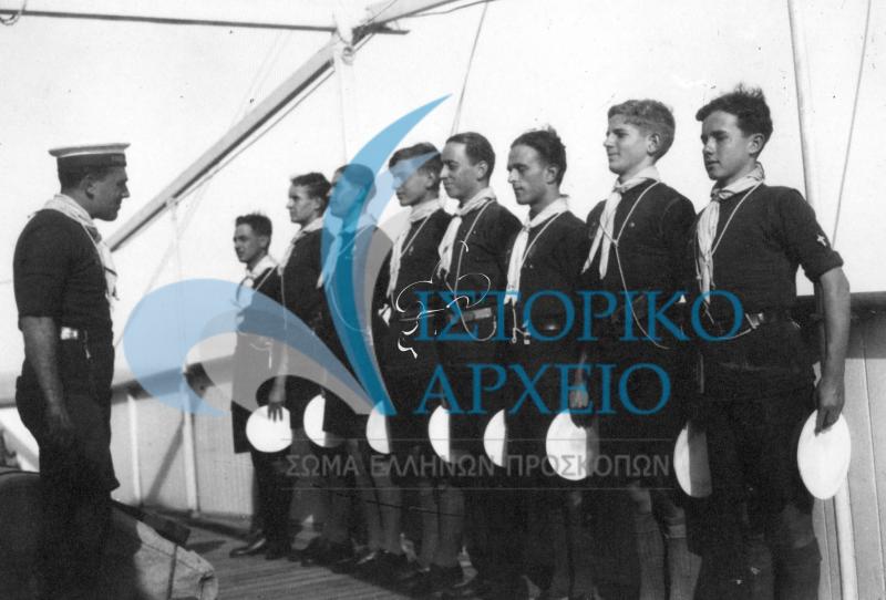 Ο  αρχηγός Α. Αντωνόπουλος δίνει το παράγγελμα "Προς επιθεώρησιν αποκαλύφθητι" προκειμένου να κάνει έλεγχο καθαριότητας στους ναυτοπροσκόπους που κατευθύνονταν στην Γαλλία το 1929. Διακρίνονται: Σαράτσογλου, Λ.Βασενχόβεν, Εμ.Κόντης, Θ.Ζαμάνος, Γ.Σπέντσας, Π.Περρωτής,  Σπύρος  Δοξιάδης,  A.Γκρώμαν. 