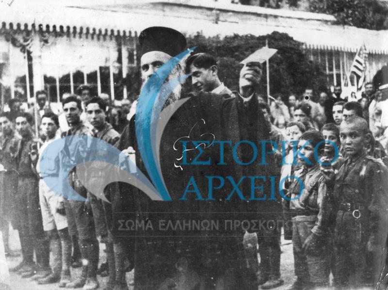 Ο Εθνομάρτυρας Μητροπολίτης Σμύρνης Χρυσόστομος μαζί με προσκόπους της Σμύρνης κρατάει στο χέρι του το Τηλεγράφημα για την απόβαση του Ελληνικού Στρατού στη Μικρά Ασία το 1919.