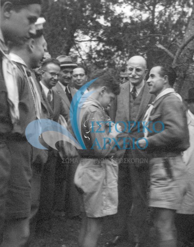 Ο Αντώνης Μπενάκης και άλλοι έφοροι συνομιλούν με προσκόπους που βρίσκονται σε εκδρομή στο πλαίσιο των εργασιών του 1ου Συνεδρίου Περιφερειακών Εφόρων που έγινε στην Αθήνα τον Απρίλιο του 1946.