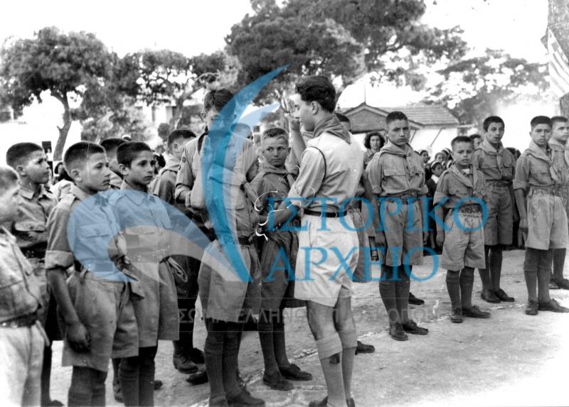 Ο αρχηγός δίνει το μαντήλι μετά την προσκοπική υπόσχεση που έδωσαν οι νέοι πρόσκοποι της ομάδας Παιδούπολης "Άγιος Χαράλαμπος" στο Ιωσηφόγλειο Ορφανοτροφείο.