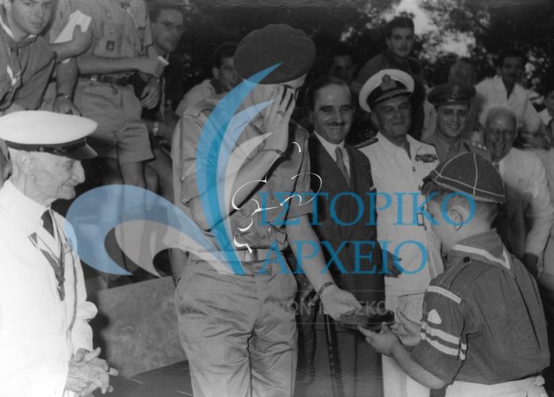 Ο Διάδοχος Κωνσταντίνος χαιρετάει Λυκόπουλο που του δίνει αναμνηστικό δώρων των ελλήνων προσκόπων κατά την Τελετή Ενηληκίωσης του Διαδόχου στο ΠΥΒΑ τον Ιούνιο του 1958.