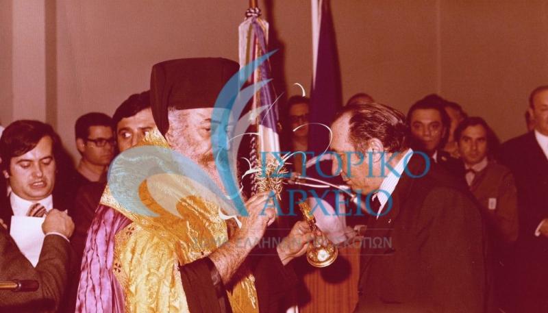 Ο Αρχιεπίσκοπος Αθηνών και Πάσης Ελλάδος Σεραφείμ ευλογεί τον Πρόεδρο ΔΣ ΣΕΠ Δ. Μαρινόπουλο κατά τα εγκαίνια του Μεγάρου "Αντ. Μπενάκης" το 1978.