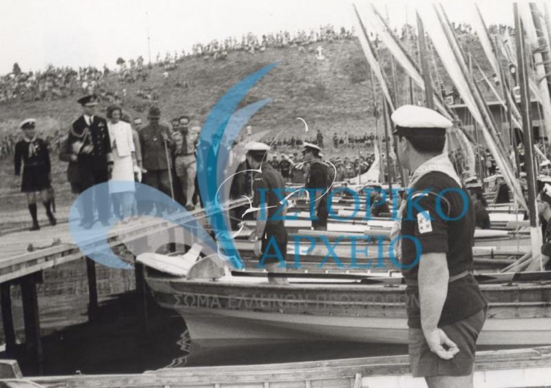 Ο Βασιλιάς Κωνσταντίνος και η Βασίλισσα Άννα - Μαρία επιθεωρούν ναυτοπροσκοπικά σκάφη κατά τα εγκαίνια του Νεώσοικου Θεσσαλονίκης το 1964. Συνοδεύονται από τον ΓΕ Δ. Αλεξάτο και τον έφορο Δ. Μακρίδη.