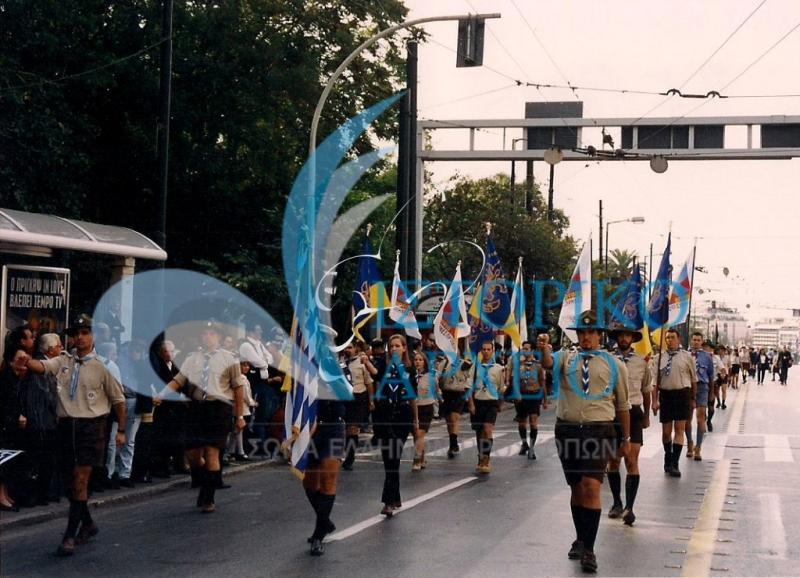 Πρόσκοποι της Π.Ε. Αθηνών στην παρέλαση για την 28η Οκτωβρίου το 2000. Πίσω από την Σημαία ακολουθούν τα αναμνηστικά σήματα για τα 90 χρόνια του ΣΕΠ.