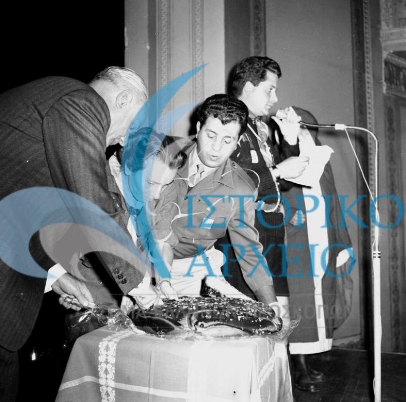 Η Αγγελική Ρουμπέση κόβει την πρωτοχρονιάτικη πίτα σε εκδήλωση του κλάδου Λυκοπούλων της ΠΕ Πρωτεούσης το 1967. Διακρίνονται: ο ΠΕ Αθηνών Δ. Γρίβας, Παντ. Δάνδολος, 