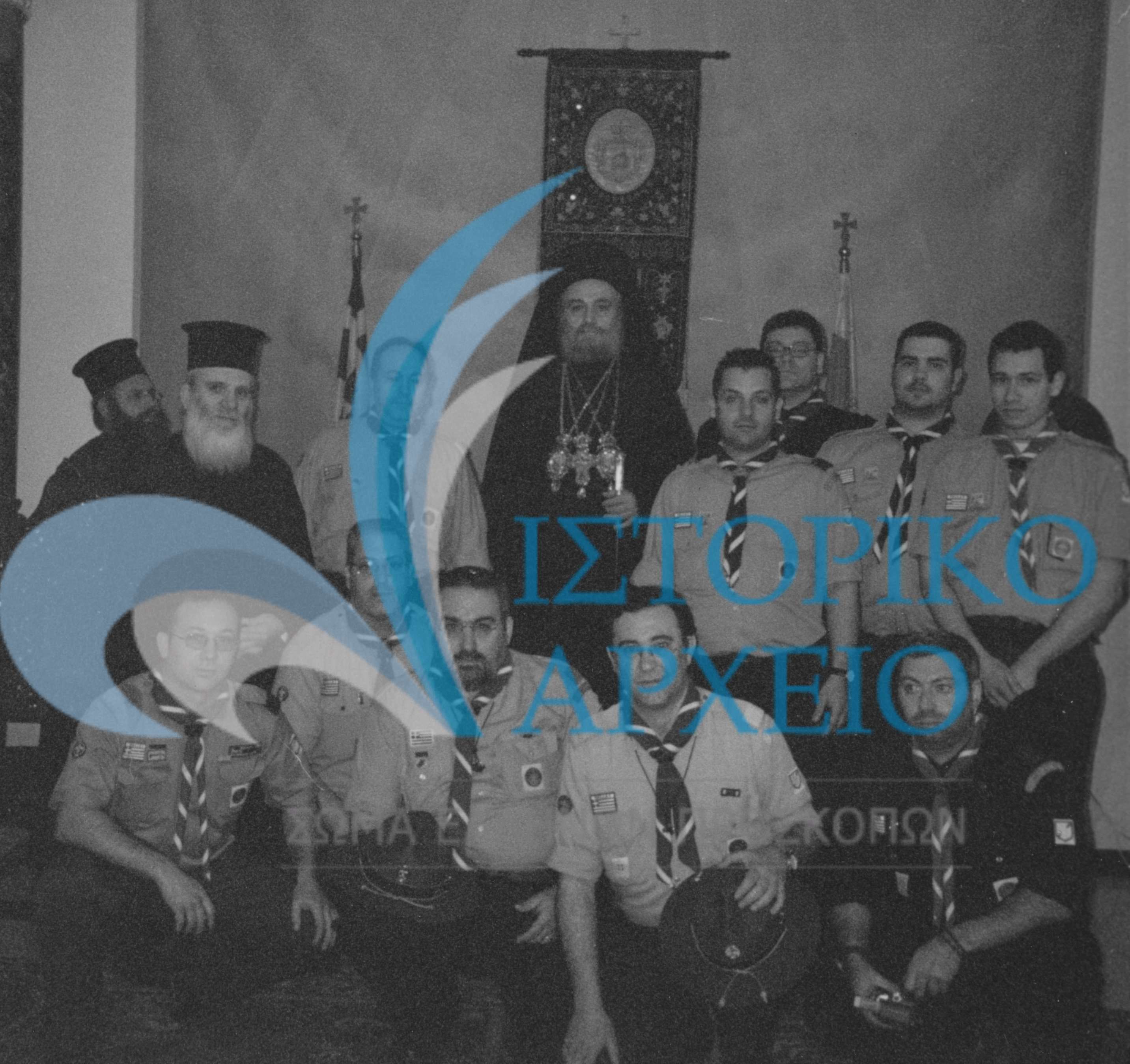 Έλληνες Πρόσκοποι με τον Πατριάρχη Ιεροσολύμων Ειρηναίο κατά την συμμετοχή τους στην τελετή αφής του Αγίου Φωτός το 2003. Διακρίνεται ο ΠΕ Λ. Μπιμπής και ο ΤΕ Δ. Σπυράκης