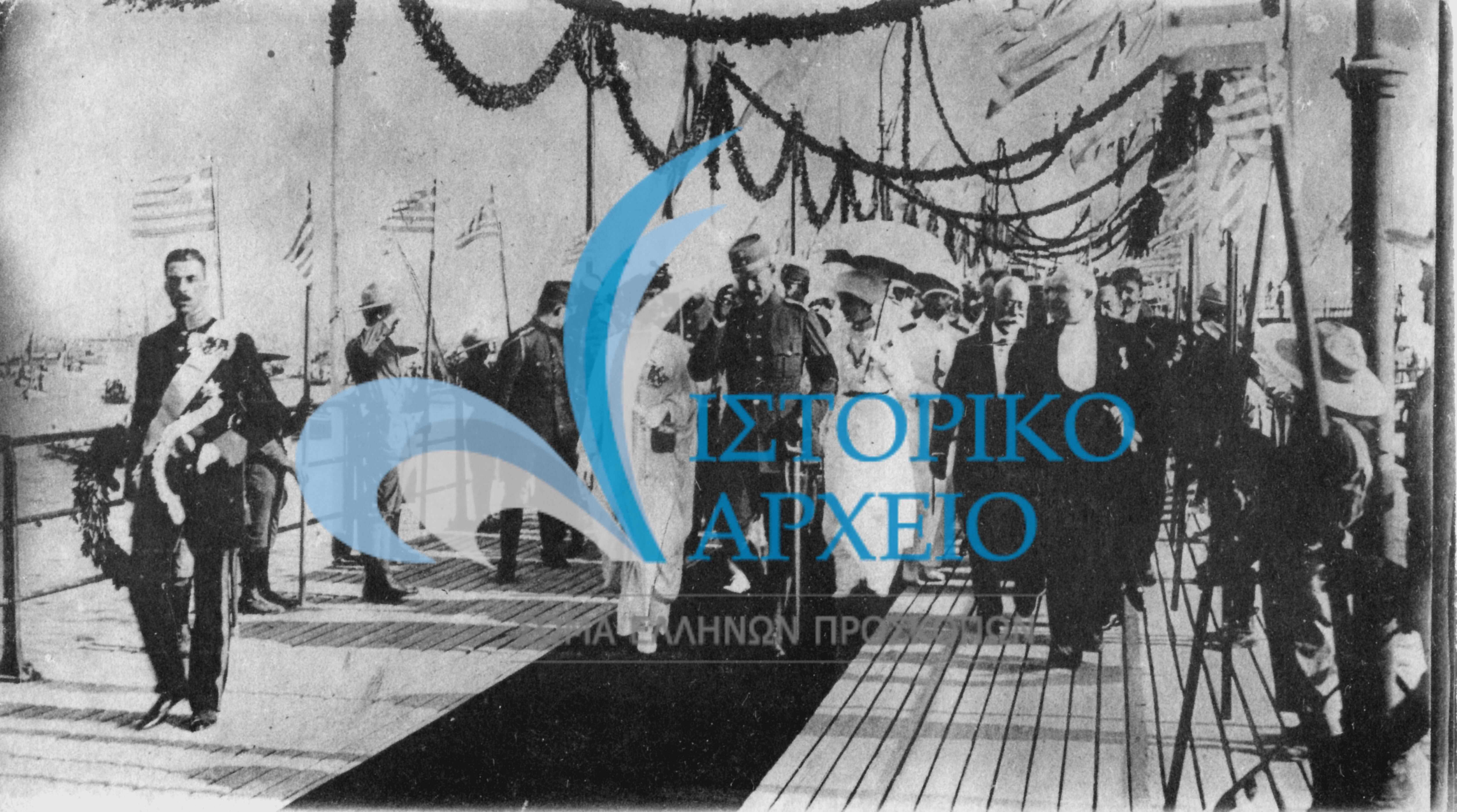 Πρόσκοποι ως τιμητικό άγημα στην υποδοχή του Βασιλιά Κωνσταντίνου στο Φάληρο το 1916 μετά τους Βαλκανικούς Πολέμους. Διακρίνονται: η Βασίλισσα Σοφία, η Πριγκίπισσα Ελένη, η Βασίλισσα Ειρήνη, ο Πρίγκιπας Παύλος, ο Υπουργός Στρατιωτικών Στράτος, ο Πρωθυπουργός Ελ. Βενιζέλος, ο Υπουργός Εξωτερικών Μιχαλακόπουλος, και ο Υπουργός Οικονομικών Κορομηλάς.