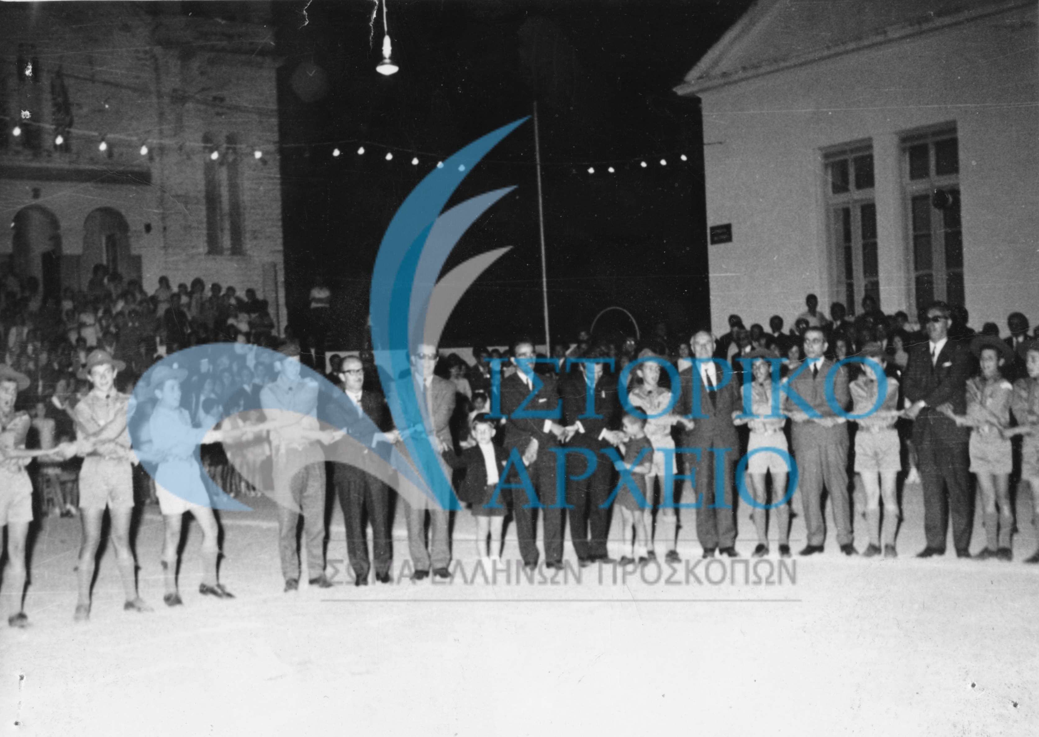 Μετά την υπόσχεση νέων λυκοπούλων του 9ου Συστήματος Αγρινίου οι παρευρισκόμενοι στο τραγούδι του αποχωρισμού στην πλατεία Αγίου Κωνσταντίνου Αγρινίου το 1971. Διακρίνονται ο Νομάρχης Ι. Καλογεράτος, ο Πρόεδρος Κοινότητας Αγ. Κωνσταντίνου, οι εκπαιδευτικοί Κωστόπουλος, Ζωγόπουλος, ο ΑΣ Α. Μαστοράκης και ο ΤΕ Αγρινίου Σπ. Ζόλδερ.