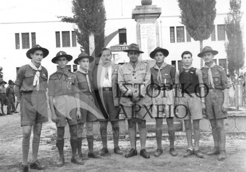 Ο ΓΕ Δ. Αλεξάτος με προσκόπους της Πρέβεζα μπροστά από το Ηρώο της πόλης, μετά τις απονομές μεταλλίων το 1948. Στο βάθος διακρίνεται το κτίριο της τότε 660 ΠΑΥΠ.