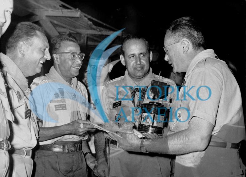 Αντιπροσωπεία των Προσκόπων της Ινδίας δίνει ως δώρο στους Έλληνες Προσκόπους την επετειακή συσκευασία τσαγίου, που συσκευάστηκε για τις αποστολές που συμμετείχαν στο Τζάμπορη του Μαραθώνα το 1963.