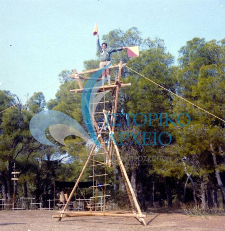 Πρόσκοπος μεταφέρει μήνυμα δια βραχιόνων πάνω σε πύργο που κατασκευάστηκε με κοντάρια στο ΠΥΒΑ το 1973.