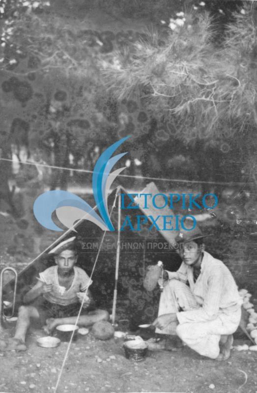 Φαγητό μπροστά από την σκηνή της ενωμοτίας στην κατασκήνωση των προσκόπων Κορίνθου στα Πεύκα Ξυλοκάστρου το 1935.